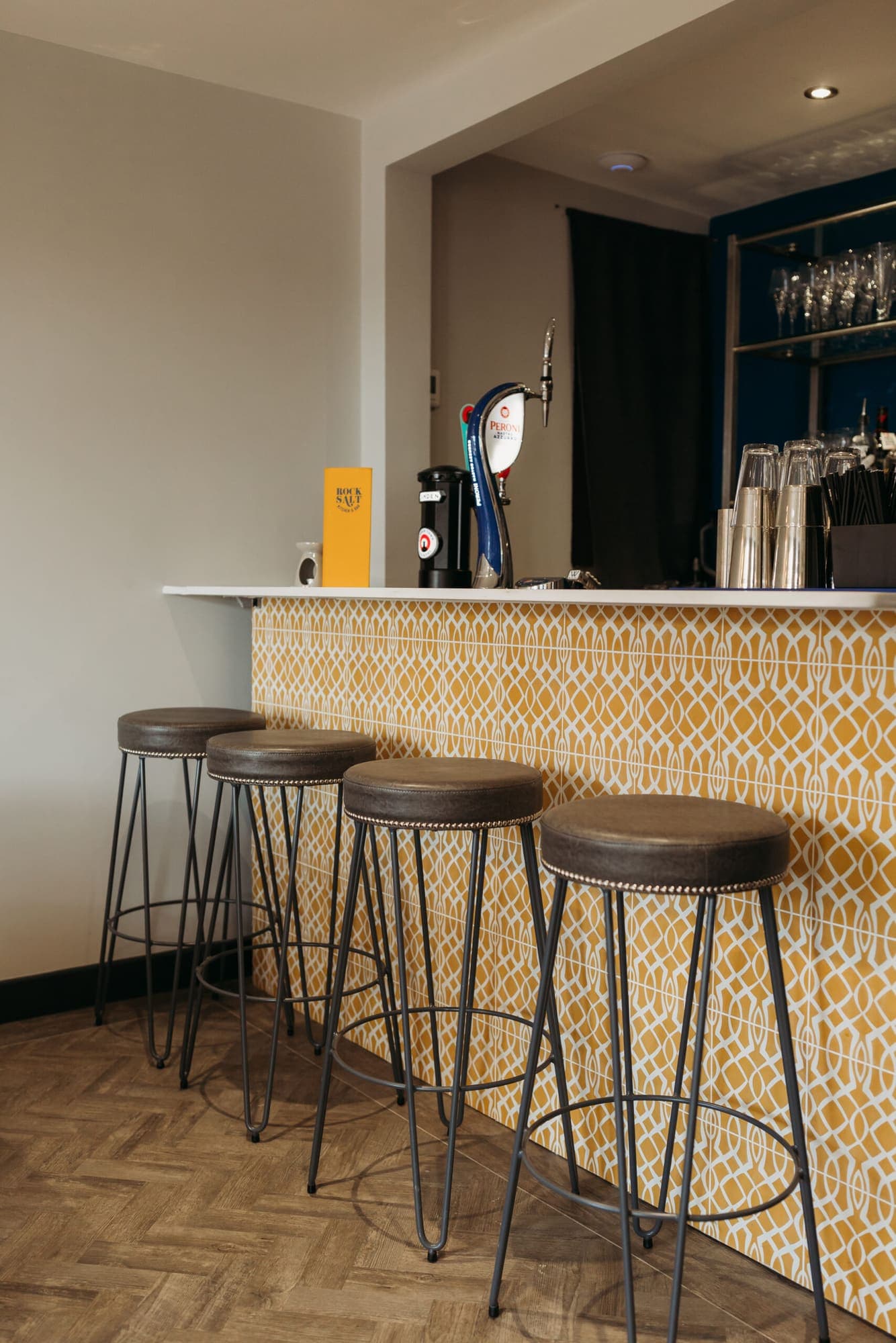 The private bar upstairs with stools along a patterned tiled counter