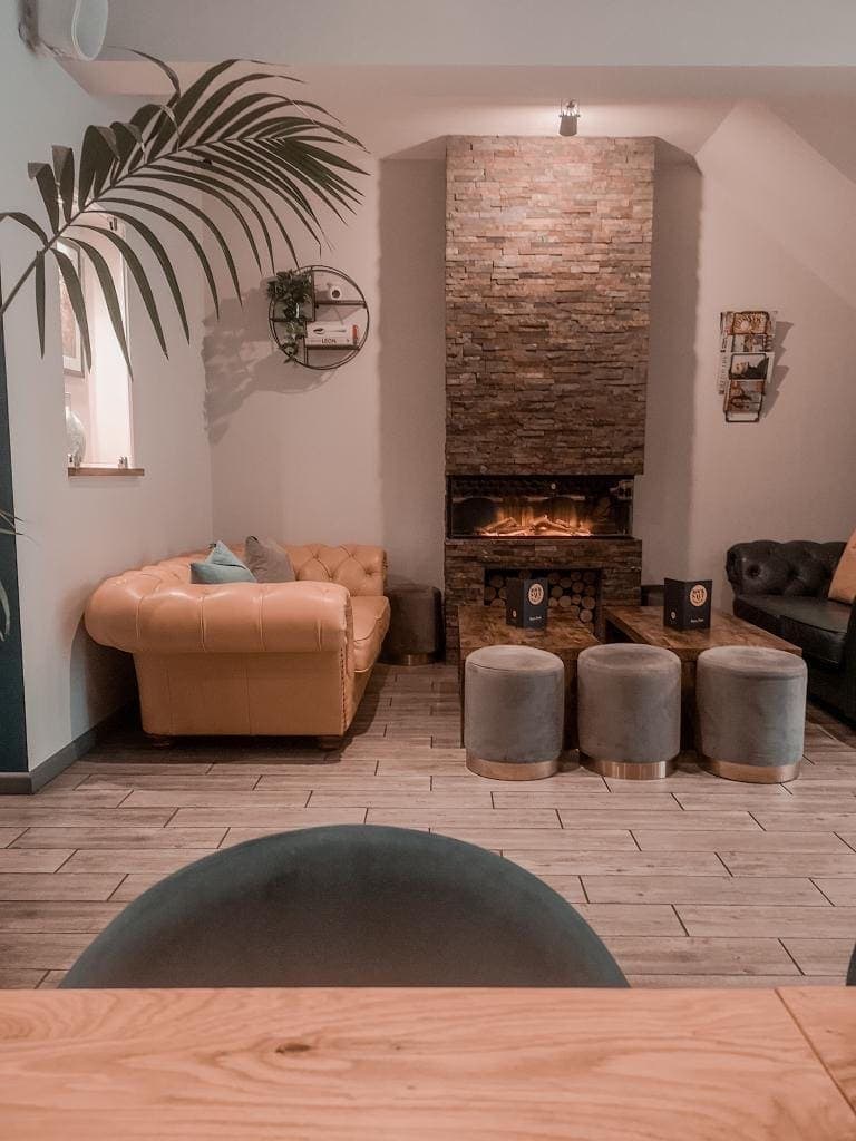 The lounge area with a blush leather sofa and a lit brick fireplace
