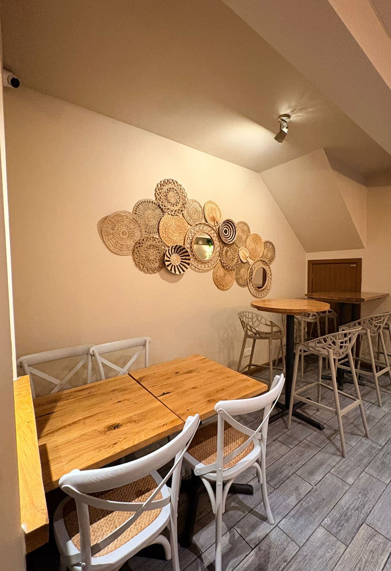 A corner table upstairs beneath a wall display of woven rattan discs