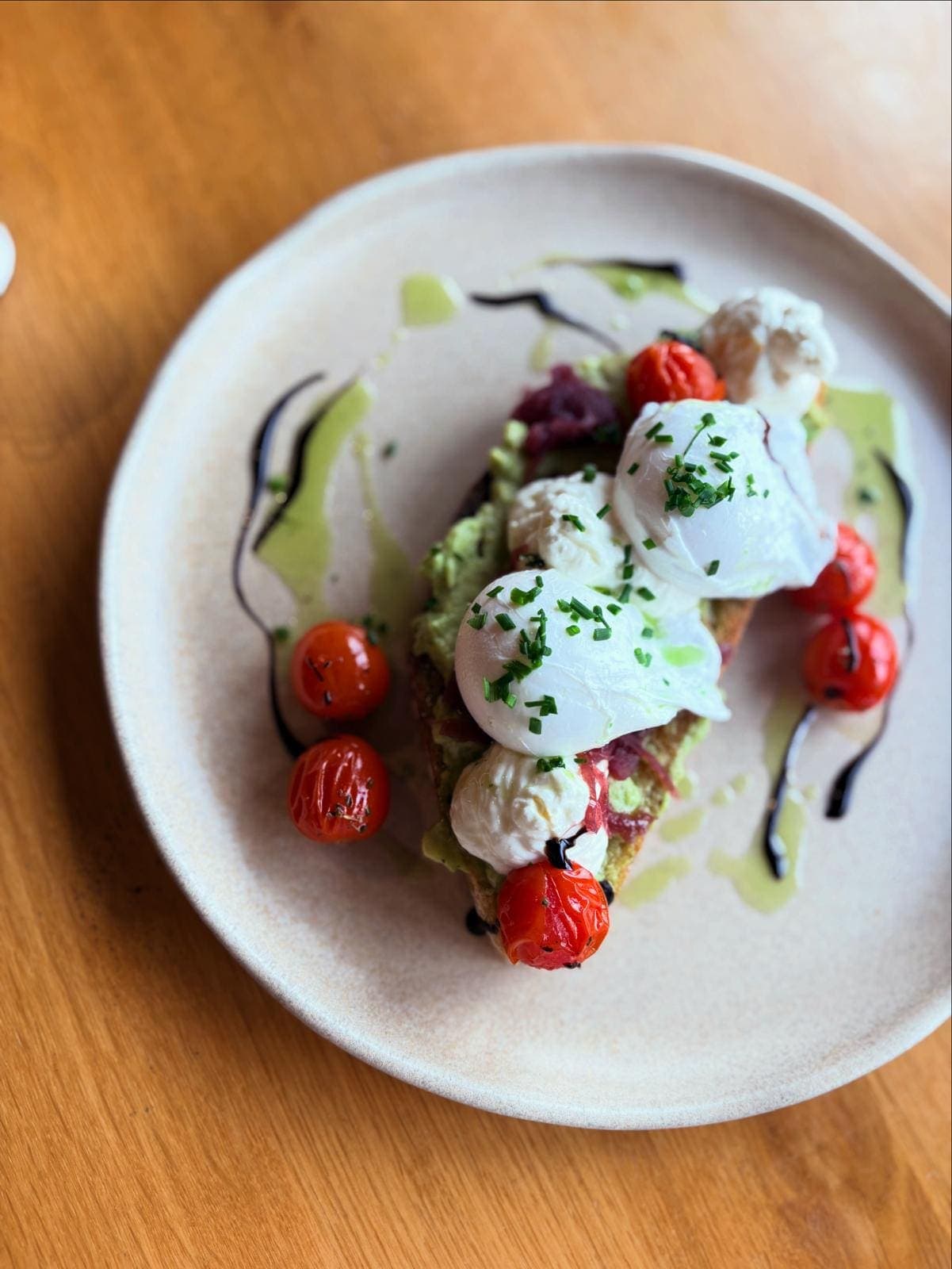 Poached eggs on smashed avocado with roast cherry tomatoes and herb oil