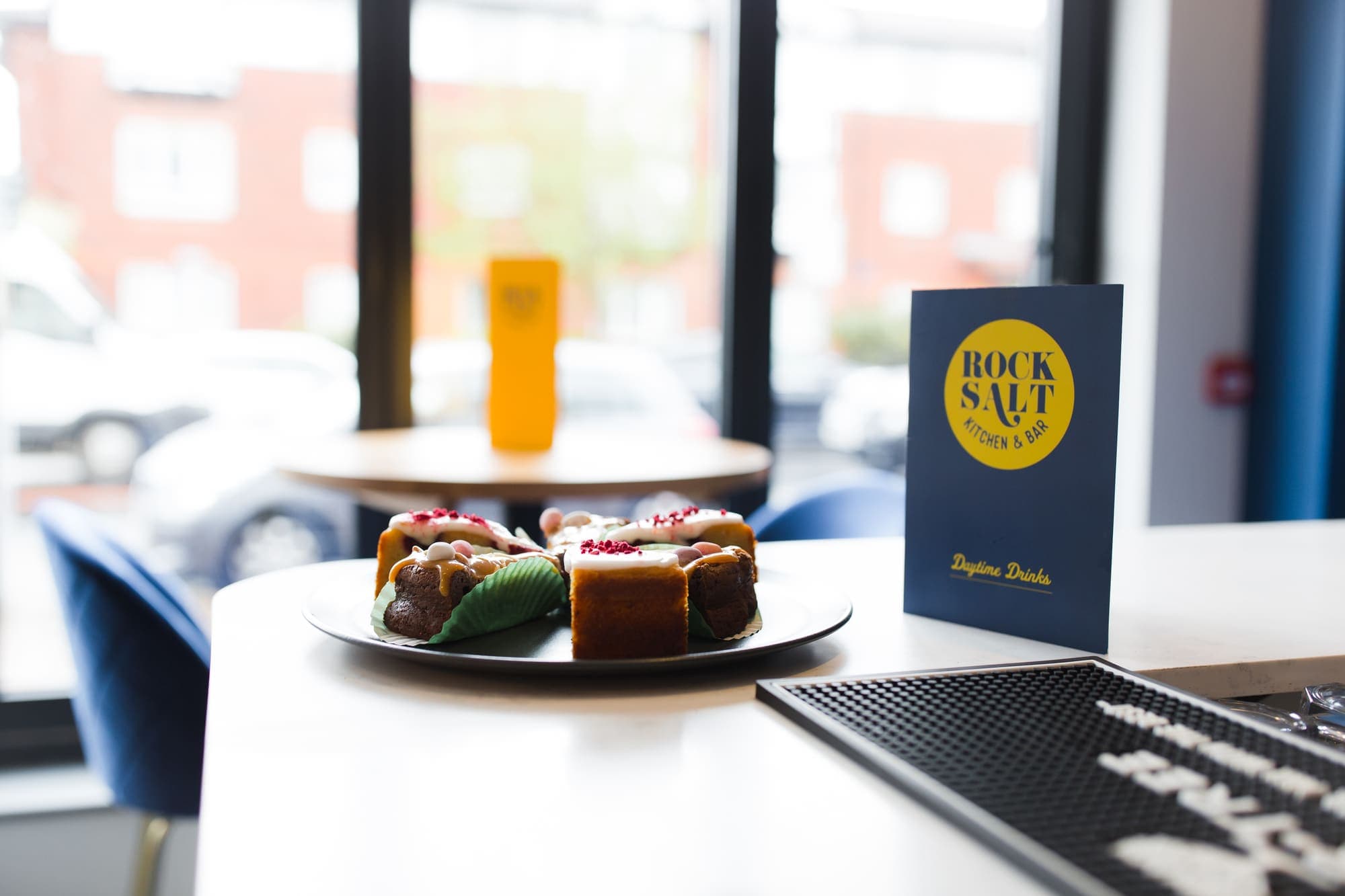 Slices of cake plated on a marble counter beside a Salt Rock menu card