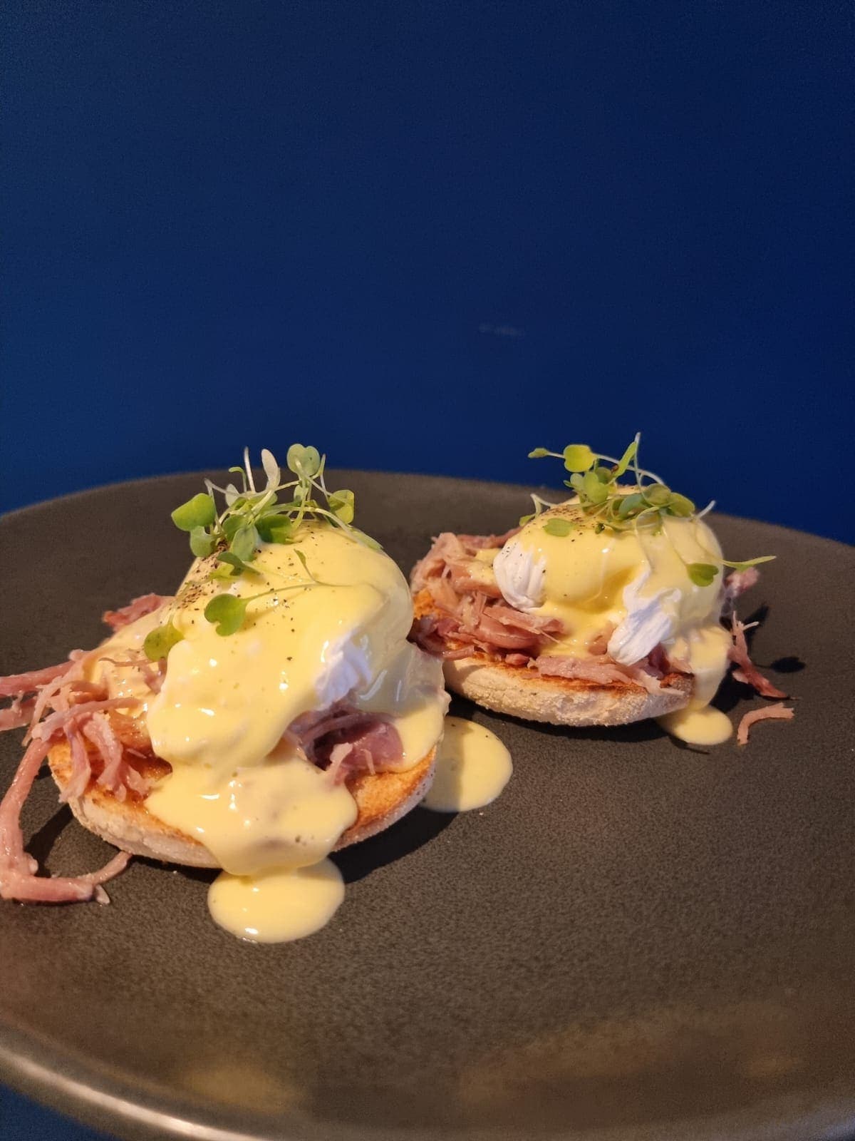 Two eggs benedict with pulled ham hock and hollandaise, finished with micro herbs