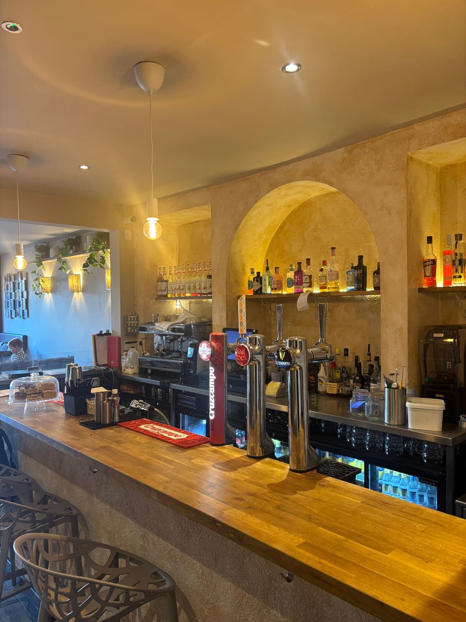 The bar at Salt Rock, with spirits lit in an arched alcove and wall lamps along the plastered wall