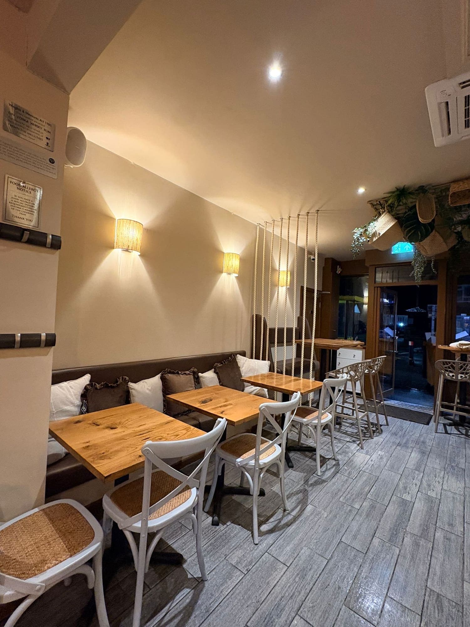 Upstairs seating with light oak tables, cane chairs and hanging greenery