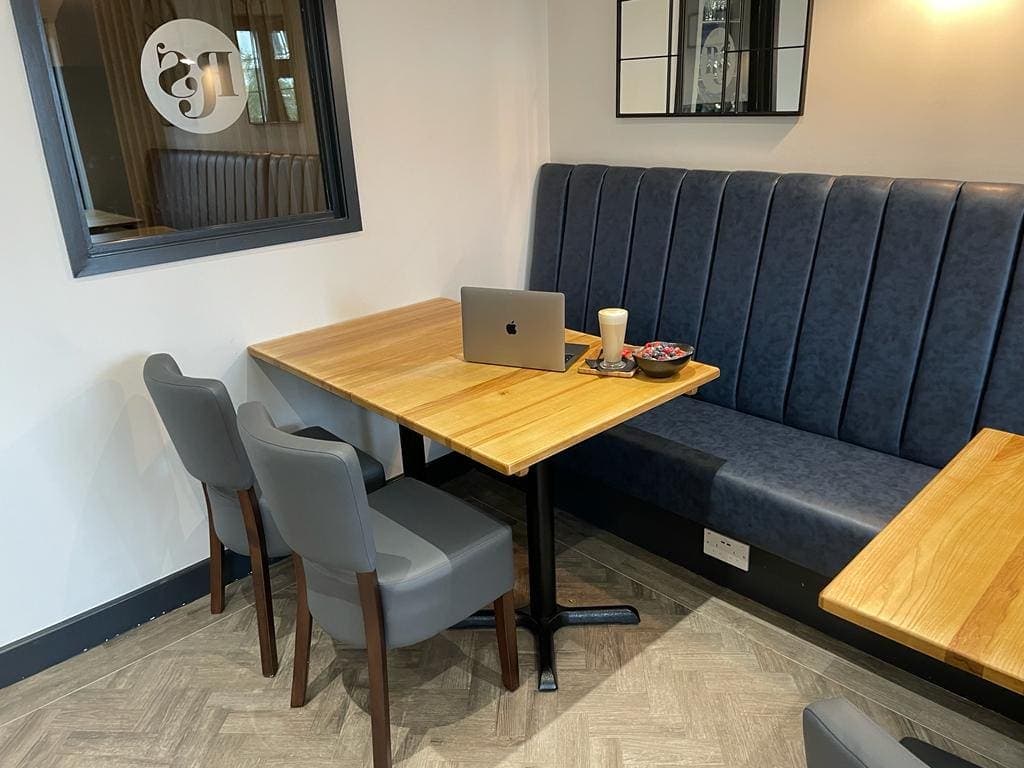 A laptop set up at a table with bench seating in the quiet work area